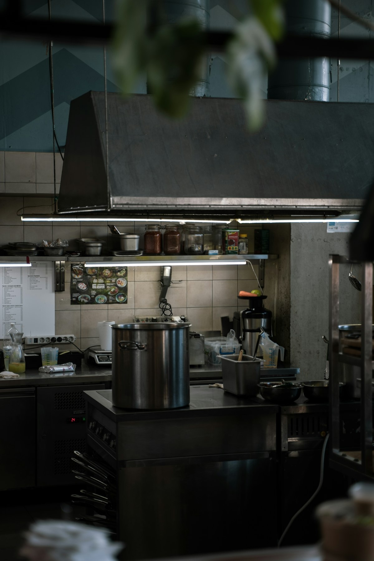 A commercial restaurant kitchen with stainless steel equipment, pots and extractor hood - Photo from Unsplash